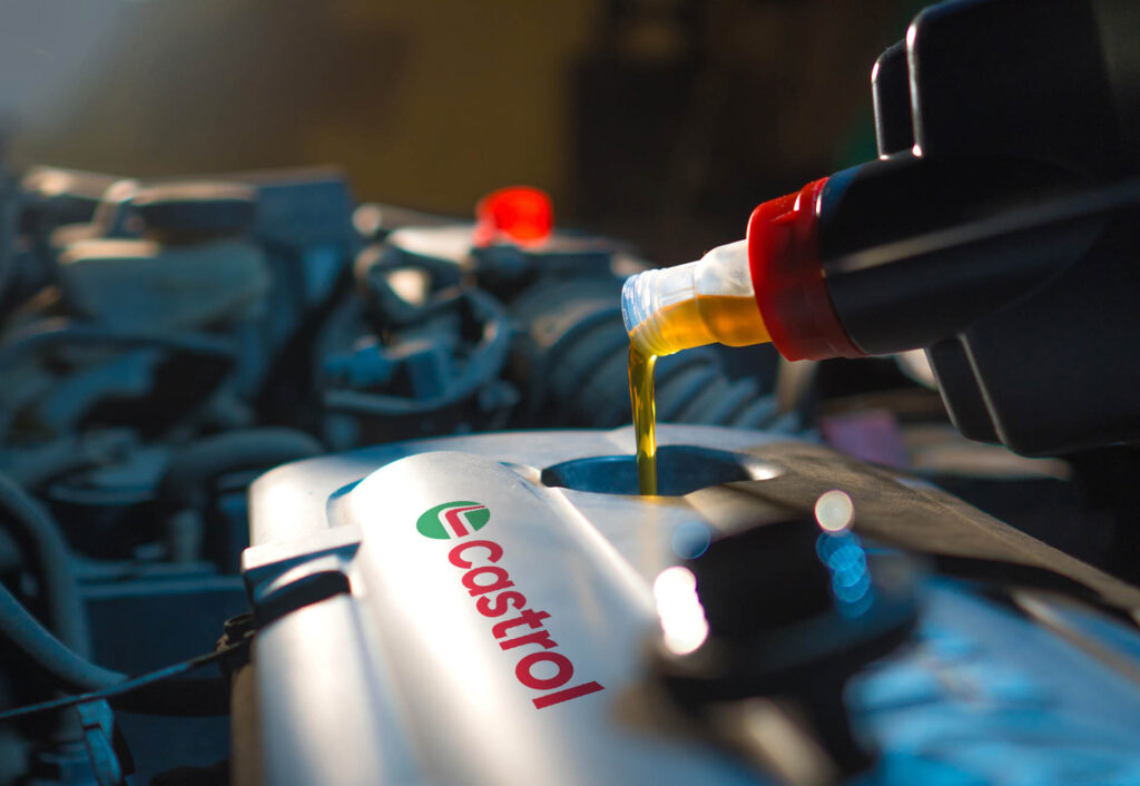 Na zdjęciu nowe logo Castrol i widoczny silnik do którego nalewany jest nowy olej.